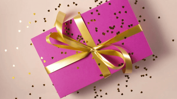 A pink corporate gift box tied with a gold ribbon