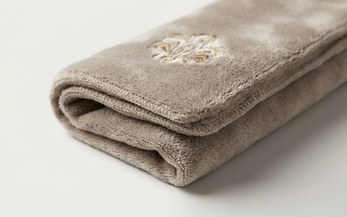 Soft folded plush fabric swatch with fine embroidery and stitching