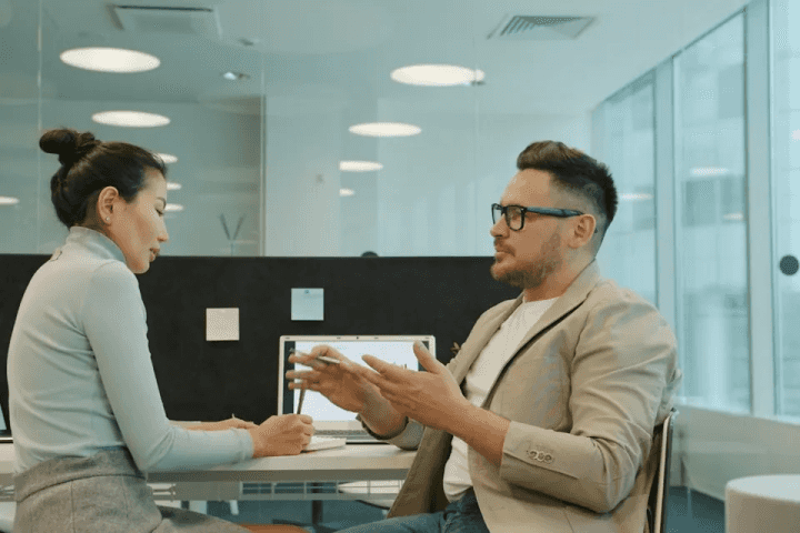 Two colleagues discussing work in a modern office